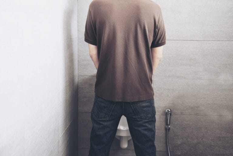 pria sedang buang air kecil di toilet berdiri sebagai ilustrasi kondisi kencing berbusa