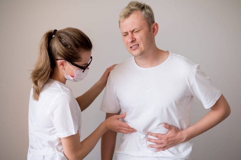 Dokter memeriksa pasien pria yang tampak kesakitan akibat nyeri perut, kemungkinan gejala gangguan ginjal seperti hidronefrosis.